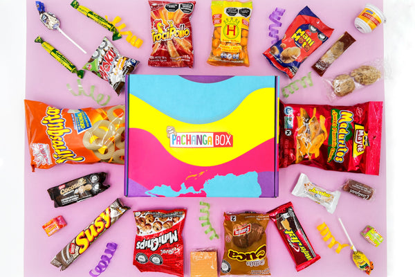 Pachanga Box with the snacks around it in a circular fashion from Colombia. The background is of pink color. 