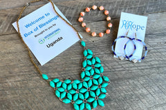 Uganda Box of Blessings featuring a Sunrise paper bead necklace, a stretchy paper bead bracelet, and Njiwa Hoops.