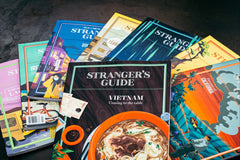 An assortment of Stranger's Guides. They include Vietnam, Lagos, Ireland, South Korea, Tehran, Scandinavia, Texas, and California.