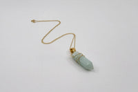 Elegant gold-plated gemstone necklace by LOKA.HAUS, laying flat on surface. Sustainable fashion, ethical luxury for social impact.
