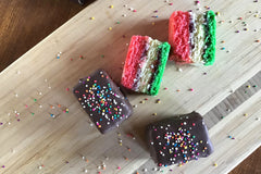 Nettie's Craft Brownies rainbow cookies sprinkles chocolate dipped aerial view of cookies on cutting board.