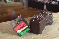 Nettie's craft brownies rainbow cookies on wood cutting board chocolate dipped rainbow sprinkles.   