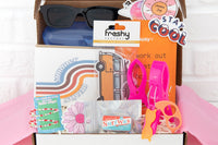 A summer-themed subscription box. Items include sunglasses in case, surf wax tin of chapstick, summer greeting card, surf van air freshener.