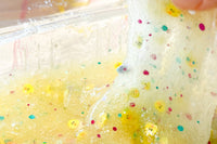 Close up of pale yellow slime with clay chicken heads and glitter in it. Chickadeedodah kit with teal and fuschia glitter.