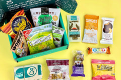 An open SnackSack subscription box filled with cranberry and almonds, cashew cookies, peanut butter cookies and more.