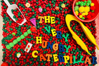 Red and green colored chick peas, rubber letters, pom pom catepillar, plastic scoop, jumbo tweezers, red, gree, and yellow pom poms 