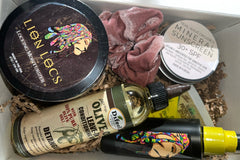 selection of products in Her Crown and Glory's Loc Box including olive oil leave-in, a scrunchie, mineral sunscreen and other products 