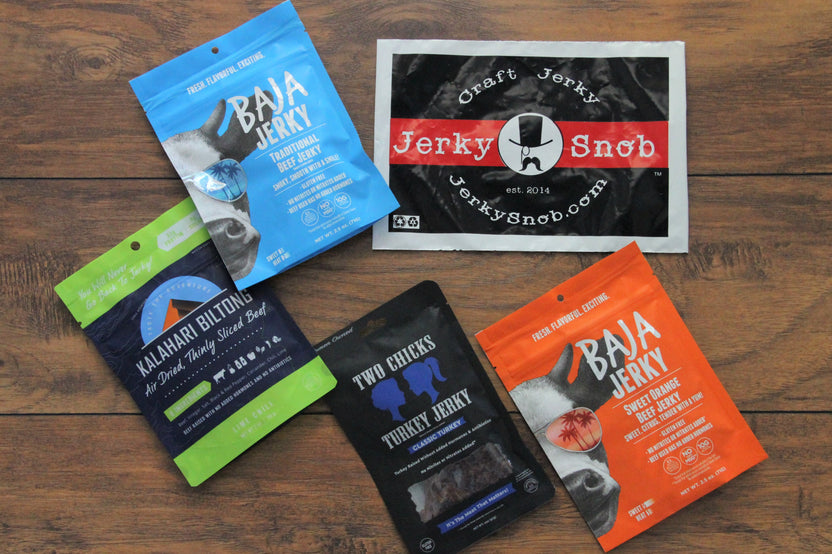 Items from a Jerky Snob subscription box including 2 different kinds of Baja Jerky packs, and a 2 Chicks Turkey Jerky pack.