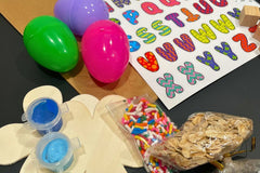 Open Activity Crate revealing contents including sprinkles, oats, plastic eggs, paint, wooden flowers and letter stickers