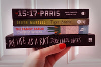 Brown box filled with a diverse collection of books in multiple genres, including crime thrillers, romance, and fantasy