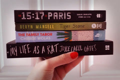 Brown box filled with a diverse collection of books in multiple genres, including crime thrillers, romance, and fantasy
