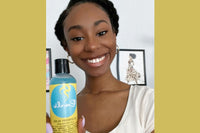 woman with a protective style smiling holding Curls Blueberry Bliss Control Jelly that was used to achieve her hairstyle 