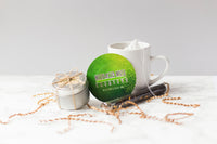 A small tin candle is tied in twine like a gift. A round green coaster is propped against a tea mug and a vial of tea.