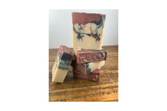 Stack of Black Raspberry Vanila soap on a wooden table with white background. The soap is swirled in pink, black and cream colors.
