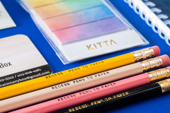 Close-up picture of notebook, pencils, stickers, pen, eraser, and business card. These items are an example of what may be included.