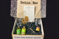 The Queen's Park Swizzle cocktail kit shown inside the box. This shows the size of the metal swizzle stick compared to the other contents.