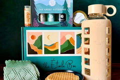 A closed Étoile subscription box surrounded by a water bottle, a stroopwaffel, candles and lip balm.