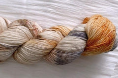 Close up photo of a hand dyed skein of sock weight yarn against a solid background. The skein is twisted and shows a variety of color.