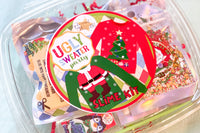 Ugly sweater party slime kit with glitter visible through small clear container behind round label with two ugly sweaters visible.