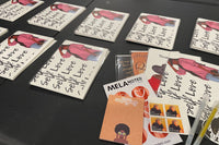 Side angle view of stacks of cards being sorted with envelope seals, stamps and a bonus pack of stickers.