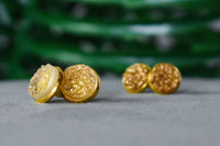 Elegant gold-plated resin earrings hand-poured by LOKA.HAUS, displayed laying flat. Sustainable fashion, ethical luxury for social impact.