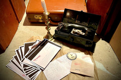 candle, suitcase, field telephone plus a selection of photocopied classified documents, a wooden cog, some letters and postcards
