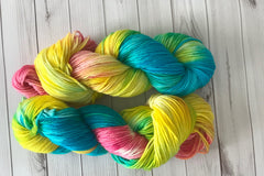 Close up photo of a hand dyed skein of sock weight yarn against a solid background. The skein is twisted and shows a variety of color.