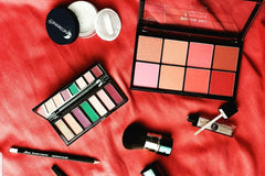Items from a Slay Glam subscription box, including makeup palettes, other makeup containers and brushes.