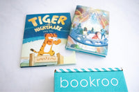 Two children reading books from Bookroo's Tween Book Club subscription on a colorful rug with additional books nearby