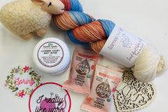 Yarn Shop Mystery Box featuring three skeins of Frog Tree Alpaca Sport yarn in green, navy, and teal with craft accessories