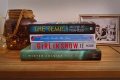 Brown box filled with a diverse collection of books in multiple genres, including crime thrillers, romance, and fantasy