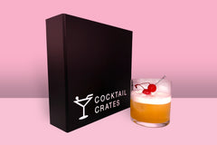A Cocktail subscription box displaying a negroni cocktail in front of a gift box from Cocktail Crates