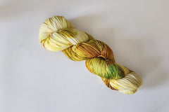 A Skein of Hand Dyed Baby Alpaca Sport Weight Yarn in a variegated colorway with yellow, gold and green 
