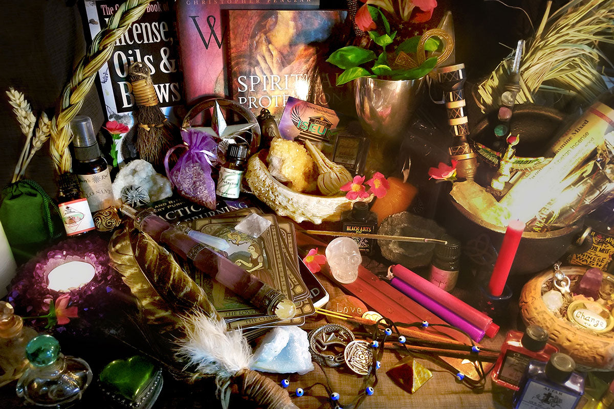 Items from a Sacred Iseum subscription box, including candles, crystals, medallions, jewelry, glass jars, and bottles.