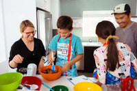 Family baking together using a BāKIT Box kit, mixing ingredients and following a recipe for a fun, hands-on kitchen experience.