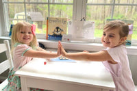 Kids happily play a number recognition game on a penguin-themed board from the Wiggle Worms preschool kit-Penguins.