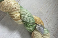 Close up photo of a hand dyed skein of sock weight yarn against a solid background. The skein is twisted and shows a variety of color.