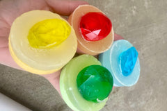 Picture shows a handful of two-toned soaps, each 2-3 oz, with embedded large plastic jewels in them in coordinating colors.
