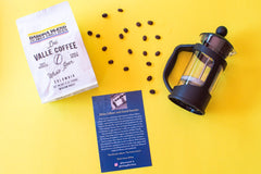 Bags of coffee and headphones along with french press. Also contains coffee beans and a flyer describing vendor.
