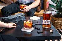 Image of two people enjoying the 101 Bourbon Bramble cocktail while playing dominos on a coffee table.