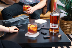Image of two people enjoying the 101 Bourbon Bramble cocktail while playing dominos on a coffee table.