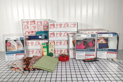 This photo is a line-up of some sewing project kits, extra fabrics, and sewing goodies that have been sent out to our members.