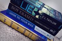 Brown box filled with a diverse collection of books in multiple genres, including crime thrillers, romance, and fantasy