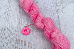 A mini Skein of Hand Dyed Merino Sock Weight Yarn and a coordinating stitch marker. Suitable for knitting and crocheting 