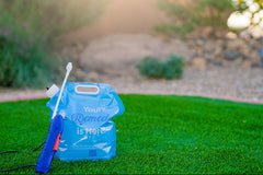 Remedy application bag and attached sprayer shown in grass. Application bag reads "Your remedy is here!"
