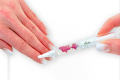 Woman's hands with natural french nails applying the Rose Botanical Nail Pen to her cuticle and nail beds.