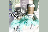 Pretty box that contains a black and white book for new baby, a rattle, a swaddle blanket and a plush toy all put together in the box.