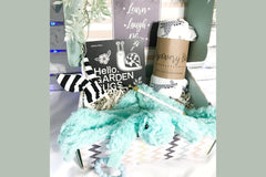 Pretty box that contains a black and white book for new baby, a rattle, a swaddle blanket and a plush toy all put together in the box.