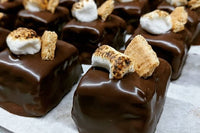 Close-up image of S'mores Brownie Bites showing chocolate covered brownie topped with a graham cracker and a toasted marshmallow.
