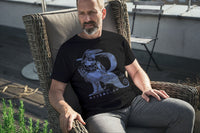 A man sitting in a chair on an outside deck wearing a Harry Potter Ravenclaw Thsirt. The design is the letter R shaped form a Raven.